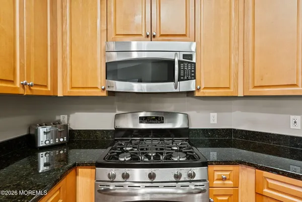 a kitchen with granite countertop a stove and a white cabinets