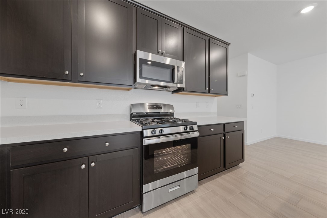 1561 Layla Crossing Avenue Henderson, NV 89002 - Photo 11 of 31 Kitchen with stainless steel appliances, recessed lighting, light stone counters, and light wood-style floors