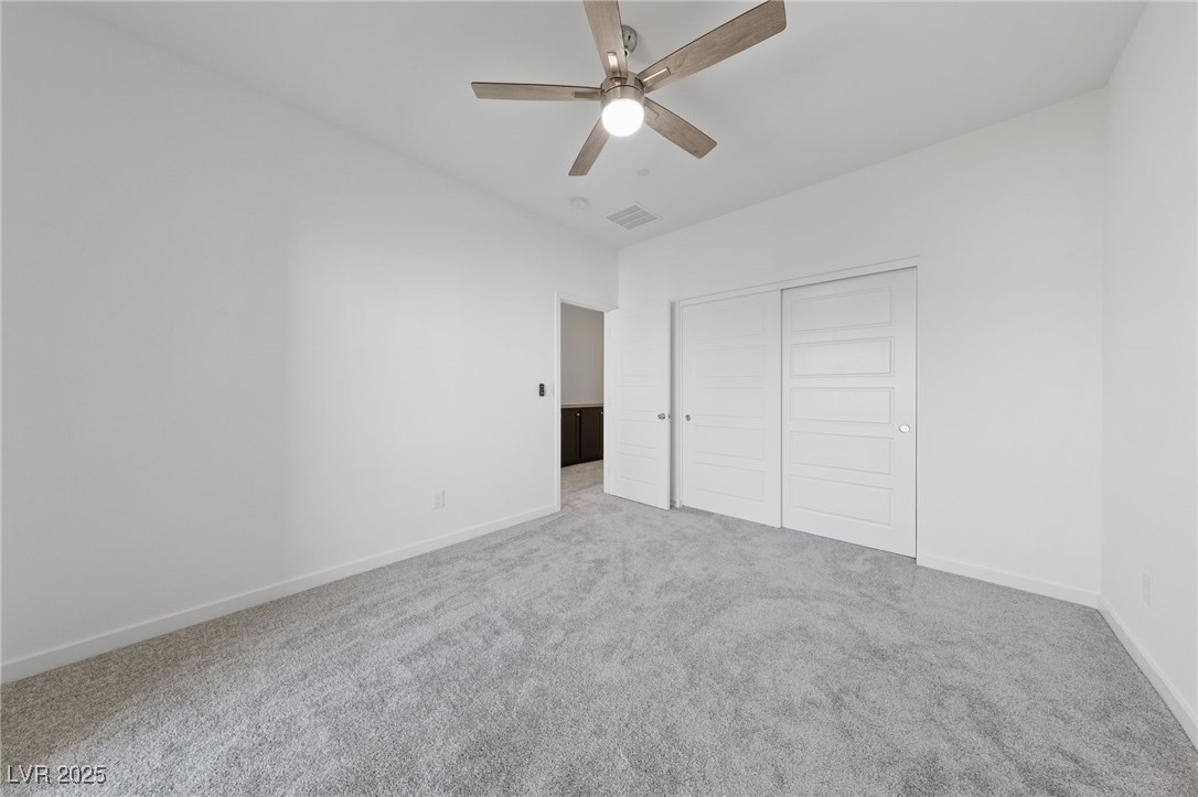 1561 Layla Crossing Avenue Henderson, NV 89002 - Photo 29 of 31 Unfurnished bedroom with light colored carpet, a closet, and a ceiling fan