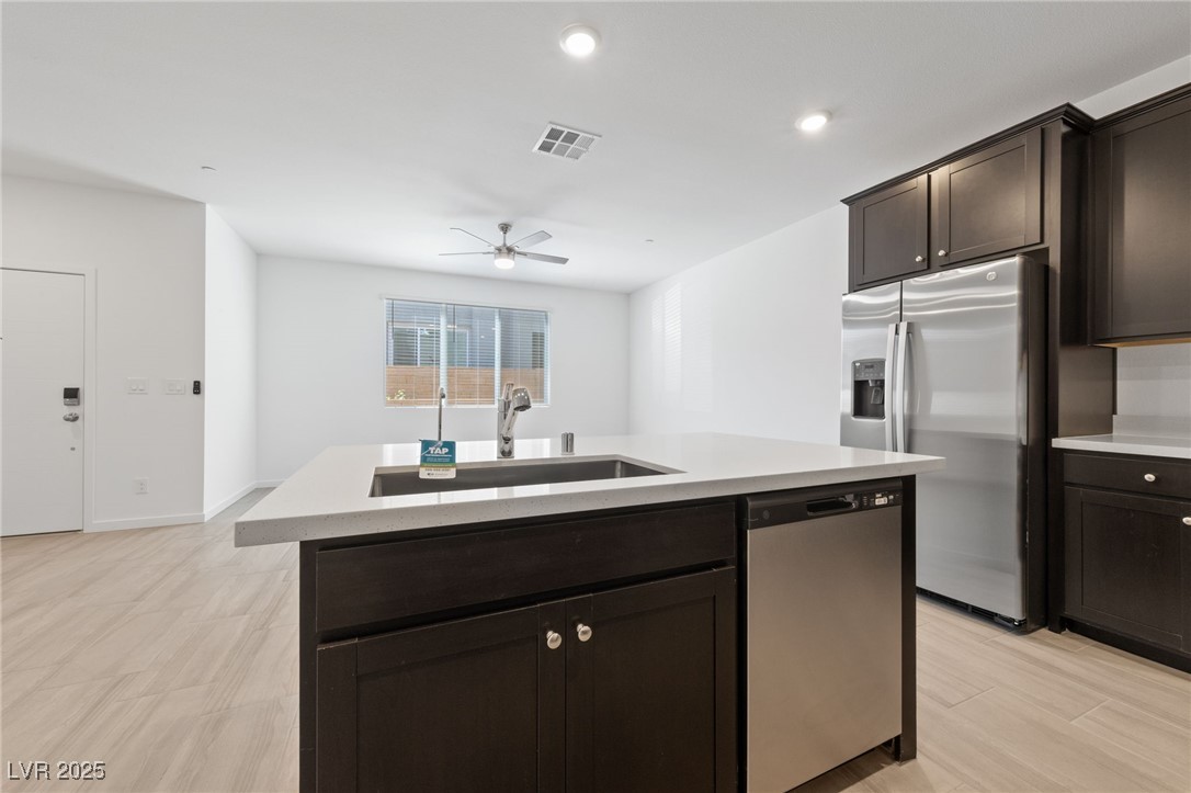 1561 Layla Crossing Avenue Henderson, NV 89002 - Photo 7 of 31 Kitchen featuring dark brown cabinets, stainless steel appliances, an island with sink, recessed lighting, and ceiling fan