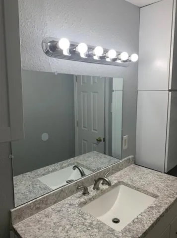 a bathroom with a granite countertop sink and a mirror