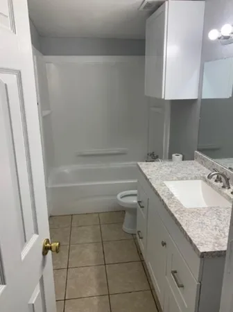 a bathroom with a granite countertop sink a toilet and shower