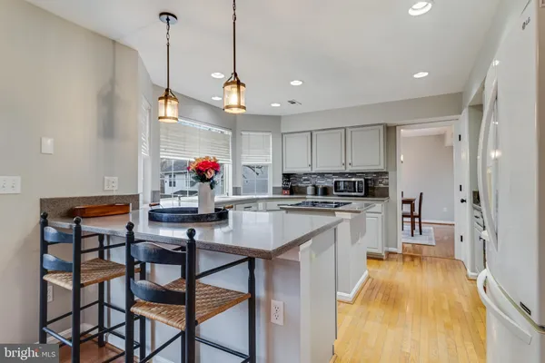 a kitchen with stainless steel appliances granite countertop a sink dishwasher a refrigerator and microwave with wooden floor