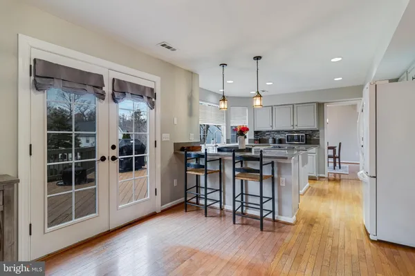 a kitchen with stainless steel appliances a dining table chairs stove and wooden floor