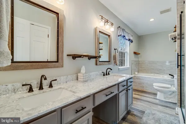a bathroom with a granite countertop sink double vanity granite tub and a mirror