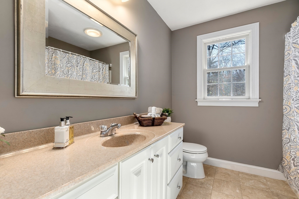 8 Brookside Lane, Unit 8 Northborough, MA 01532 - Photo 18 of 24 a bathroom with a granite countertop sink a toilet and a window