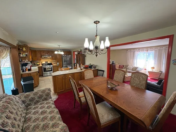 a view of a dining room and livingroom with furniture wooden floor a rug a painting and a chandelier