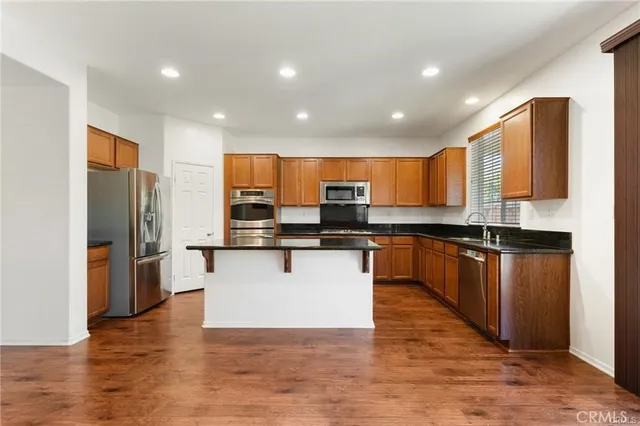a kitchen with stainless steel appliances granite countertop a refrigerator a stove top oven and a sink