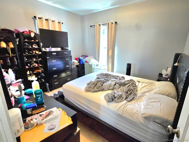 a bedroom with a bed window and a flat screen tv