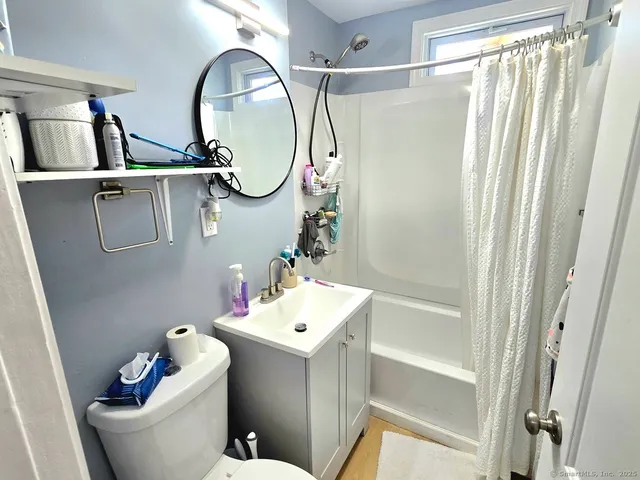 a bathroom with a toilet sink vanity tub and mirror