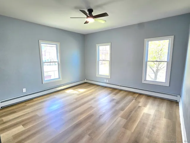 a view of empty room with wooden floor and fan