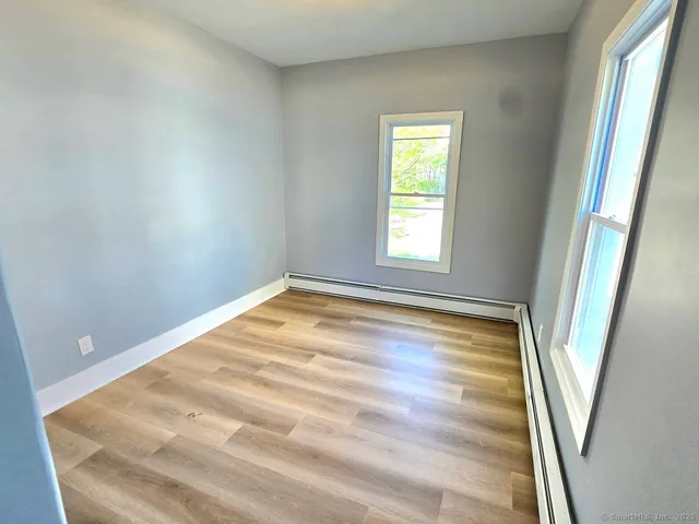 a view of empty room with wooden floor and fan