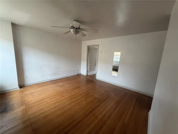 an empty room with wooden floor fan and windows
