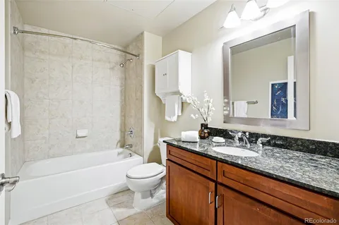 a bathroom with a granite countertop bathtub shower sink and toilet
