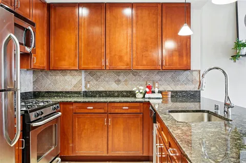 a kitchen with granite countertop a sink a stove and cabinets