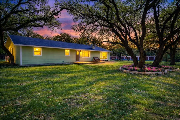 a view of a house with a big yard and a large tree