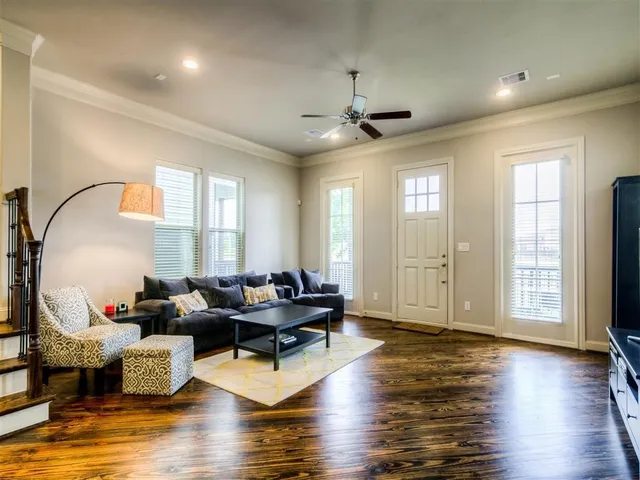 a living room with couches and a dining table with wooden floor