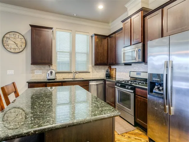 a kitchen with stainless steel appliances granite countertop a sink a stove and a refrigerator