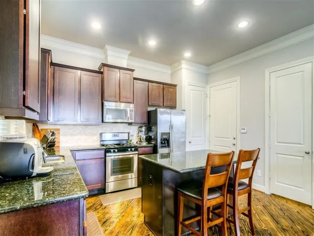 a kitchen with kitchen island granite countertop wooden cabinets and stainless steel appliances