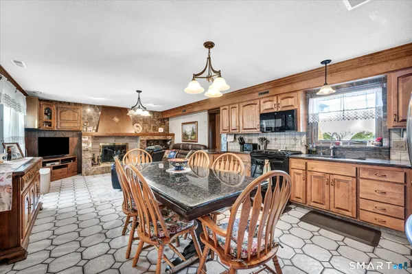 a kitchen with stainless steel appliances granite countertop a stove top oven a refrigerator a sink a dining table and chairs with wooden floor