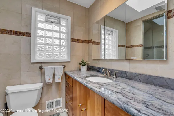 a bathroom with a granite countertop toilet sink and mirror