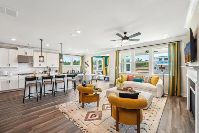 a living room with furniture kitchen view and a large window