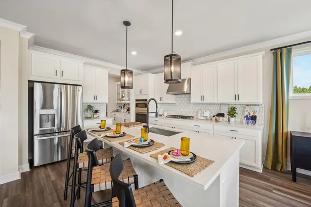 a kitchen with a refrigerator a stove a sink dishwasher and white cabinets with wooden floor