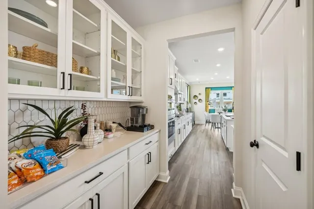 a hallway with a lot of white cabinets and wooden floor