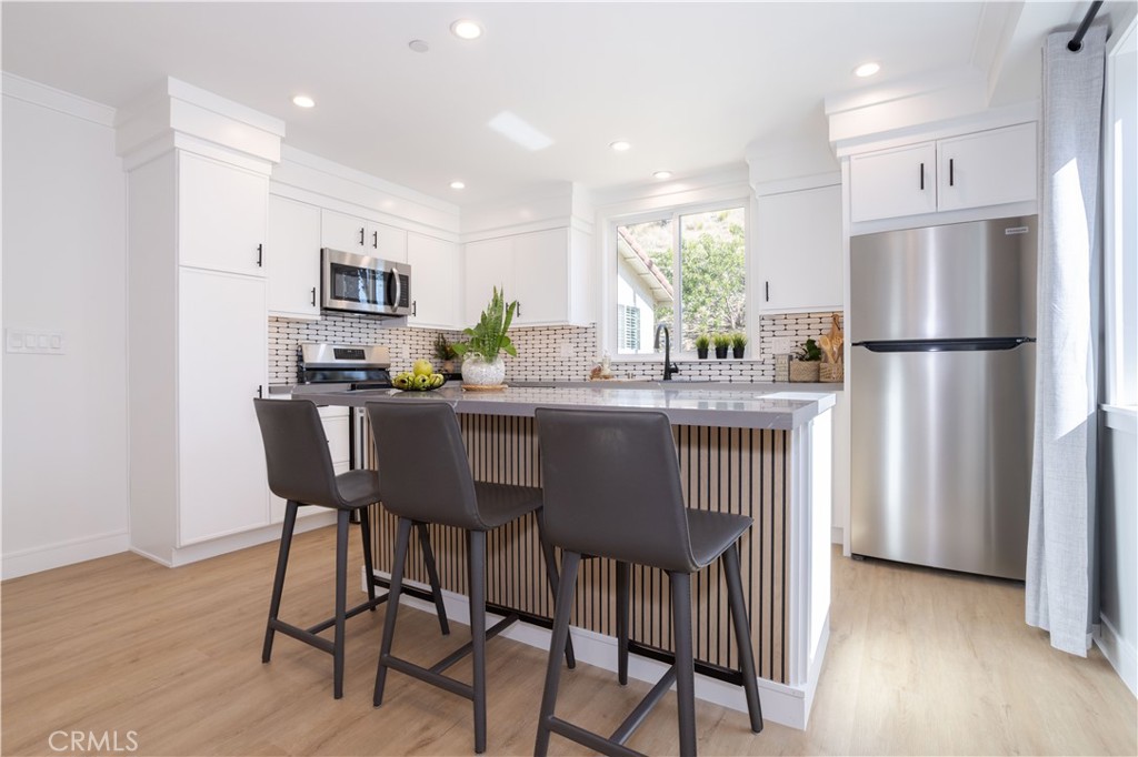 19429 Singing Hills Drive Porter Ranch, CA 91326 - Photo 12 of 26 a kitchen with stainless steel appliances a dining table chairs refrigerator and sink