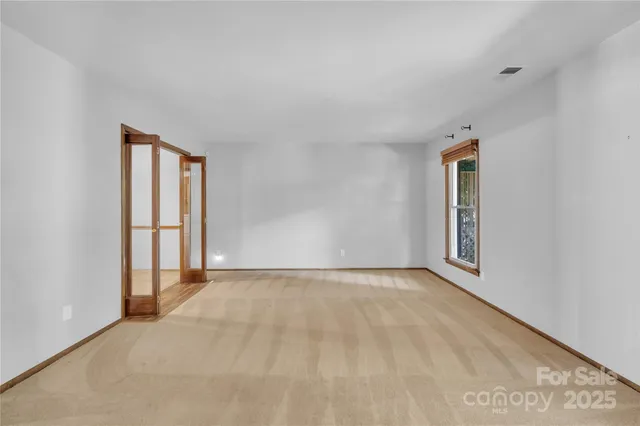 a view of an empty room with window and wooden floor