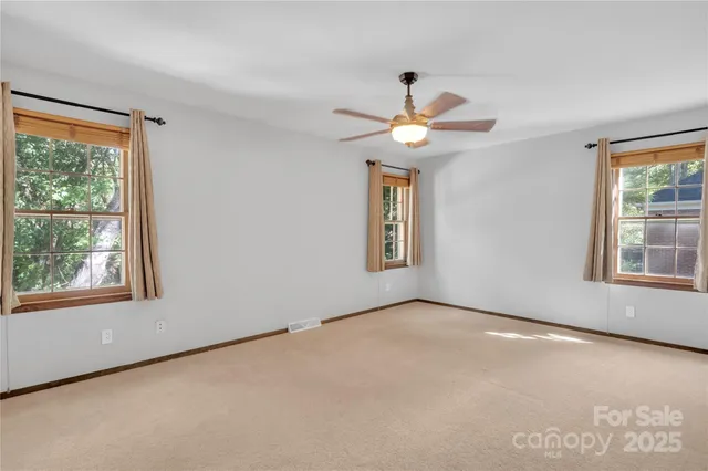 an empty room with windows and chandelier fan