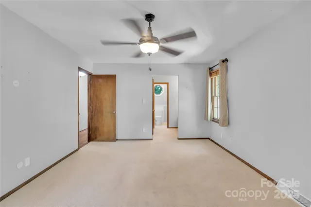 an empty room with chandelier fan and windows