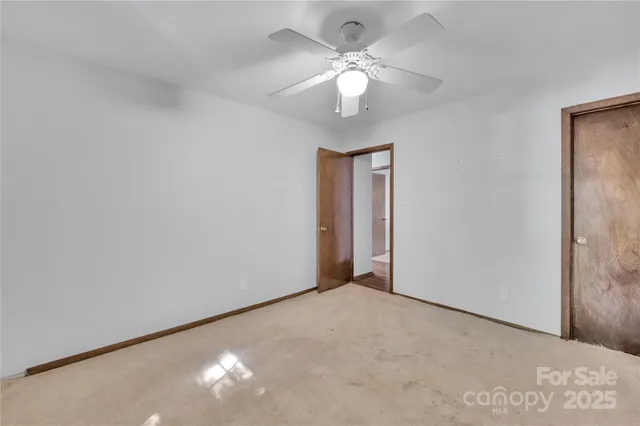 a view of an empty room with a chandelier fan