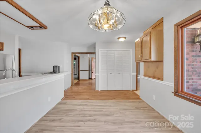 a large white kitchen with wooden floor and chandelier
