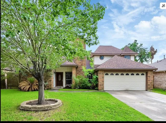 a front view of a house with a yard and tree