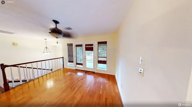 a view of a hallway with wooden floor and a bathroom