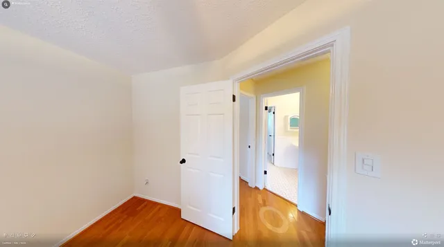 a view of a hallway with wooden floor and a bathroom