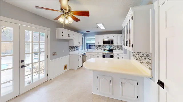 a kitchen with stainless steel appliances a white cabinets counter space and a window