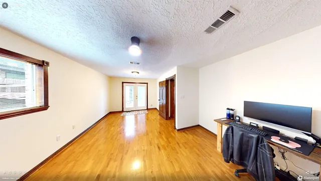 a view of an empty room with wooden floor and a window
