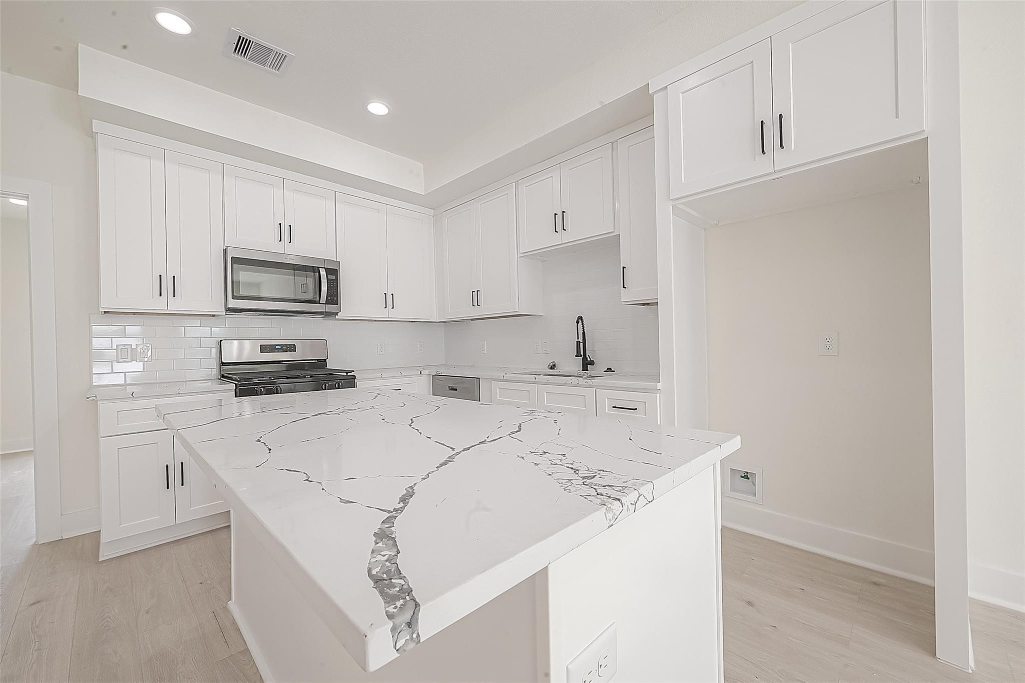 4135 Mallow Street, Unit A Houston, TX 77051 - Photo 8 of 12 a kitchen with kitchen island white cabinets and stainless steel appliances