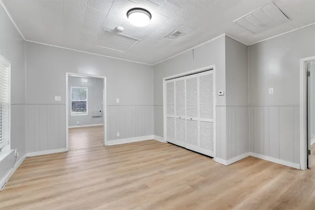 an empty room with wooden floor and windows