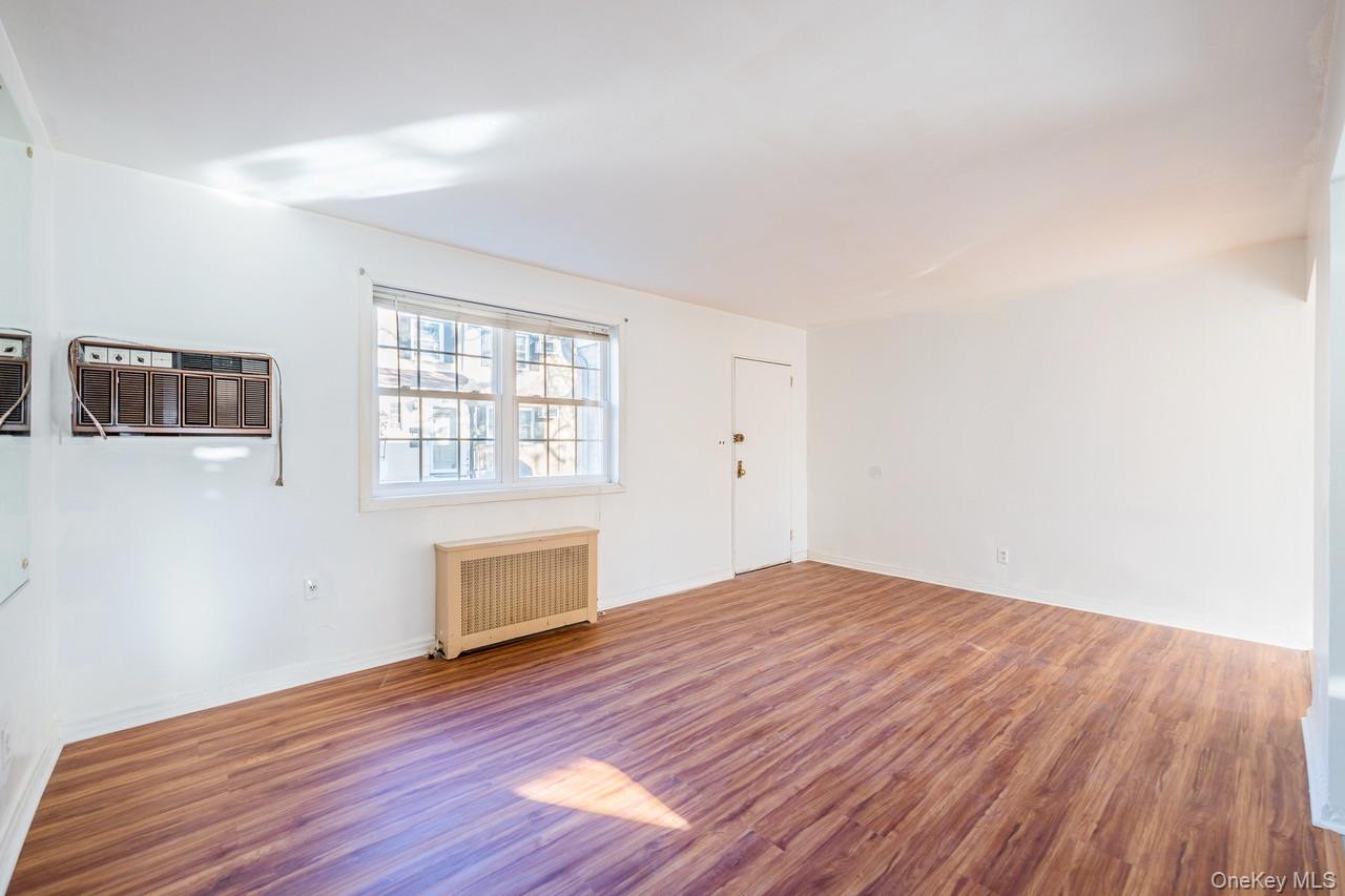 222-17 69th Avenue, Unit 17A Queens, NY 11364 - Photo 7 of 10 an empty room with wooden floor and windows