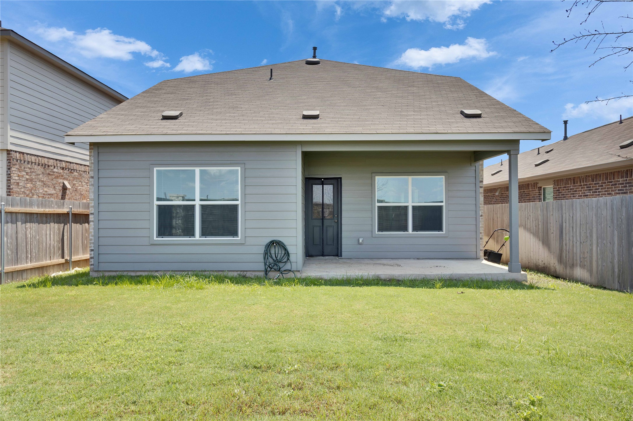 206 Canley Loop Hutto, TX 78634 - Photo 5 of 31 Back of house featuring a fenced backyard, a patio area, and a shingled roof.
