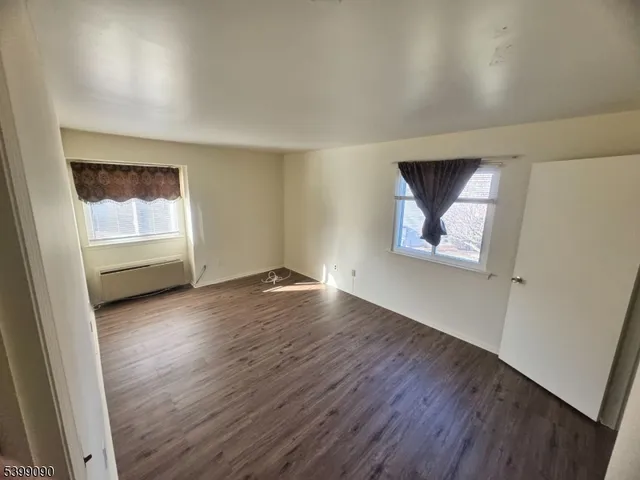 an empty room with wooden floor cabinet and windows