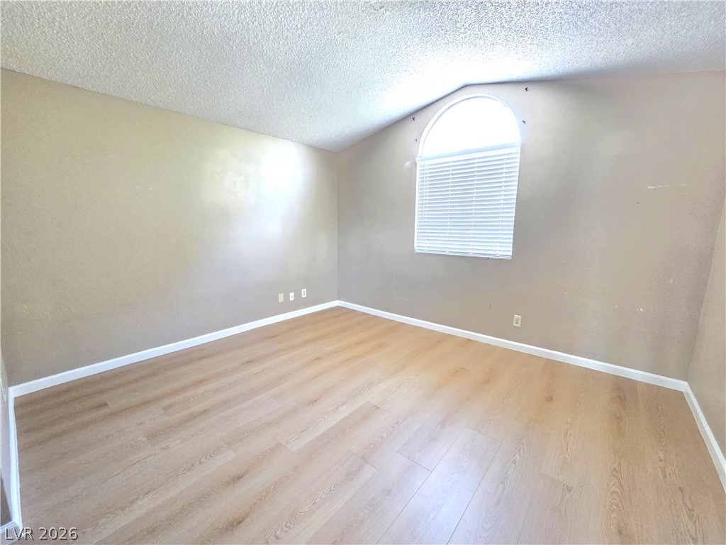 2882 Sandyfalls Way Las Vegas, NV 89142 - Photo 8 of 18 A well-lit bedroom with vaulted ceilings and a charming arched window.
