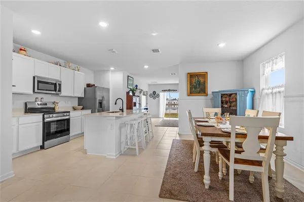 a kitchen with microwave a refrigerator and chairs