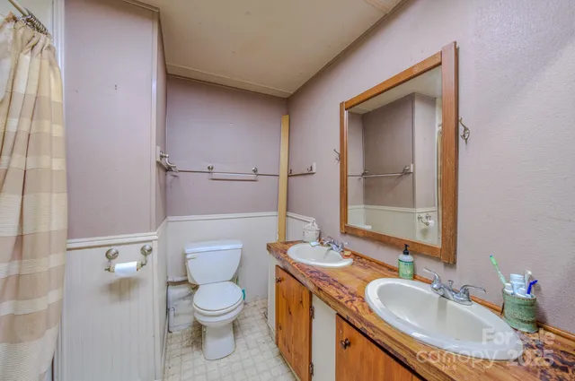 a bathroom with a granite countertop toilet a sink and a mirror