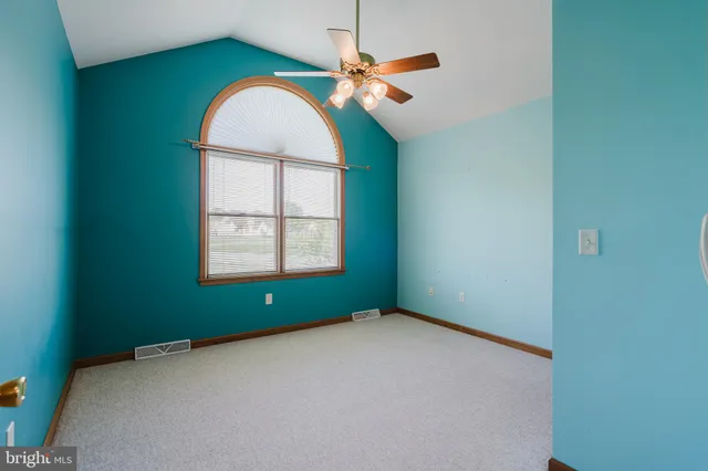 an empty room with a window and chandelier fan