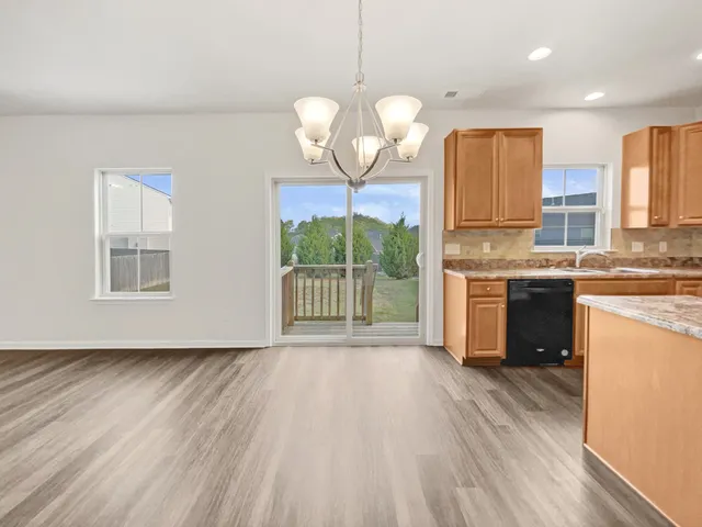 a kitchen with stainless steel appliances granite countertop a stove a sink dishwasher a refrigerator white cabinets and wooden floor next to a window