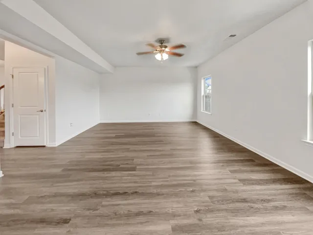 a view of empty room with wooden floor and ceiling fan
